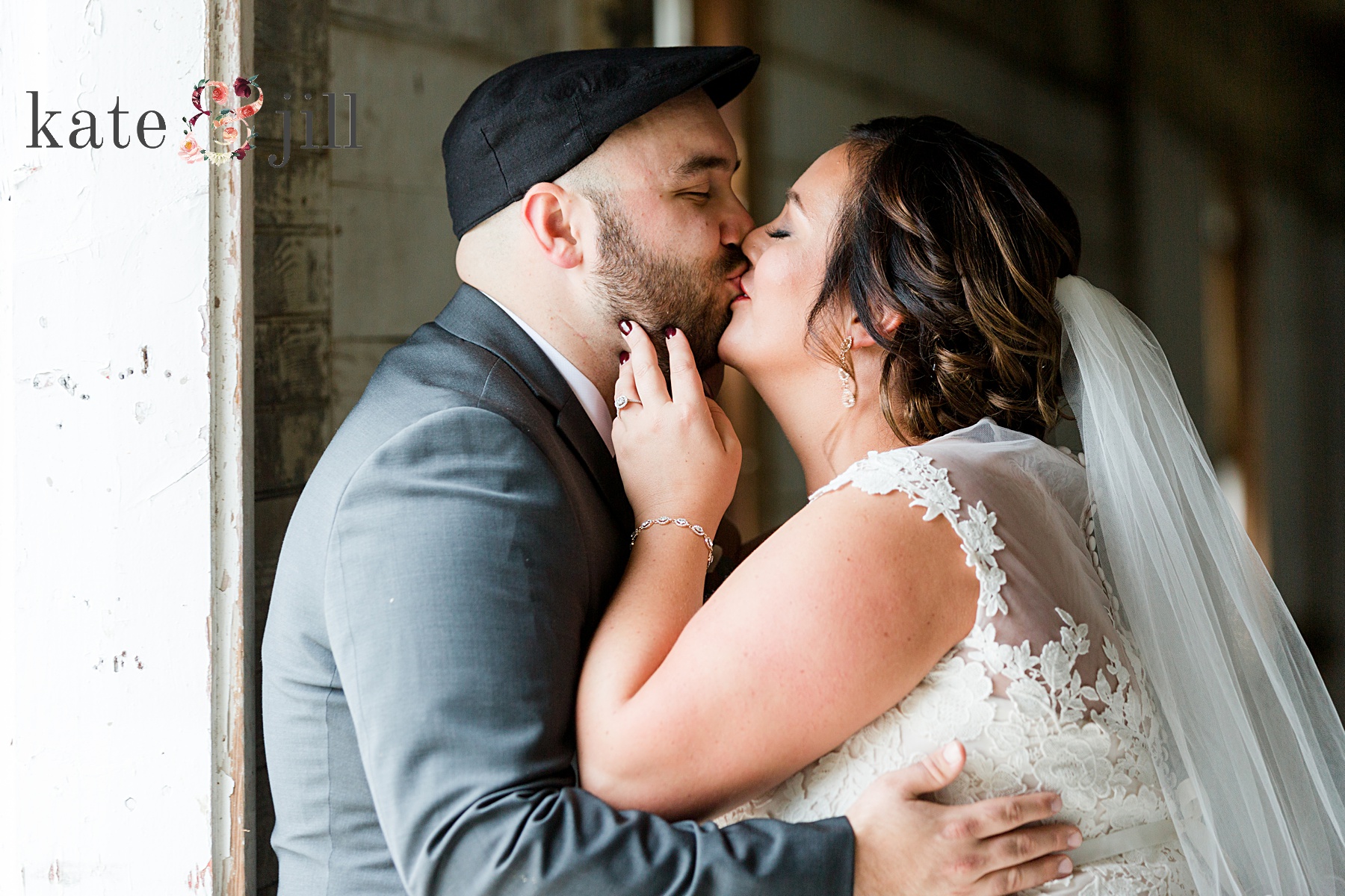 bride and groom kissing inside barn