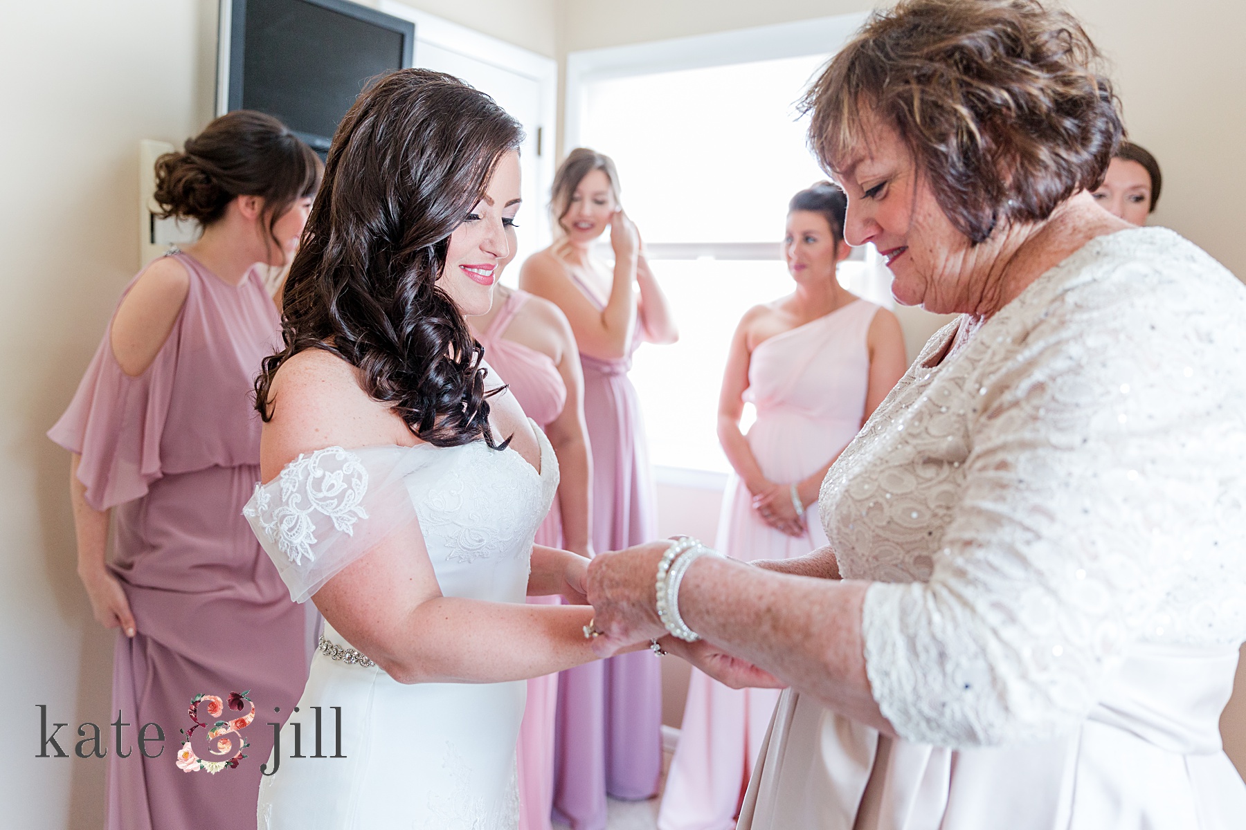 mom putting jewelry on the bride
