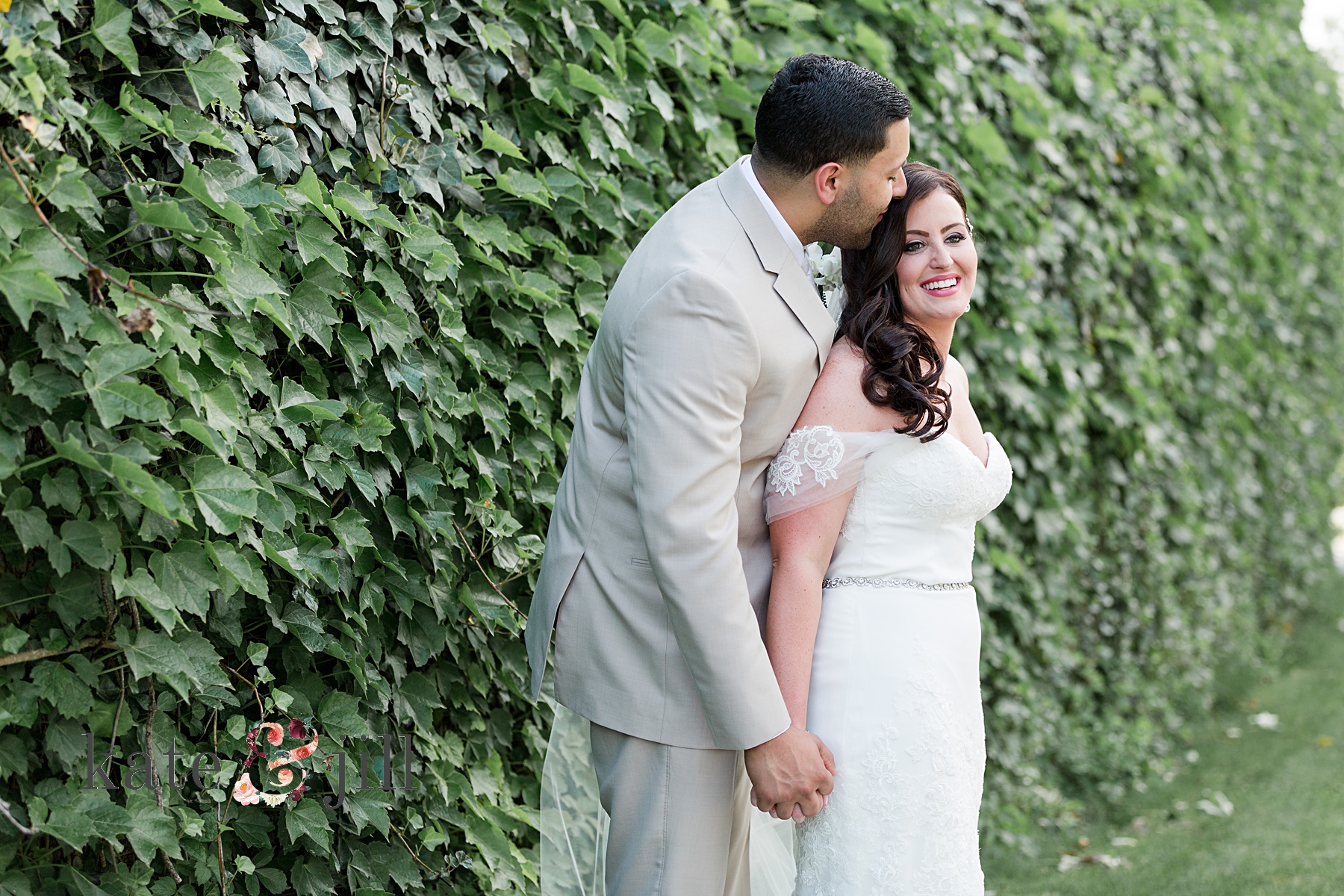 bride and groom in front of ivy wall
