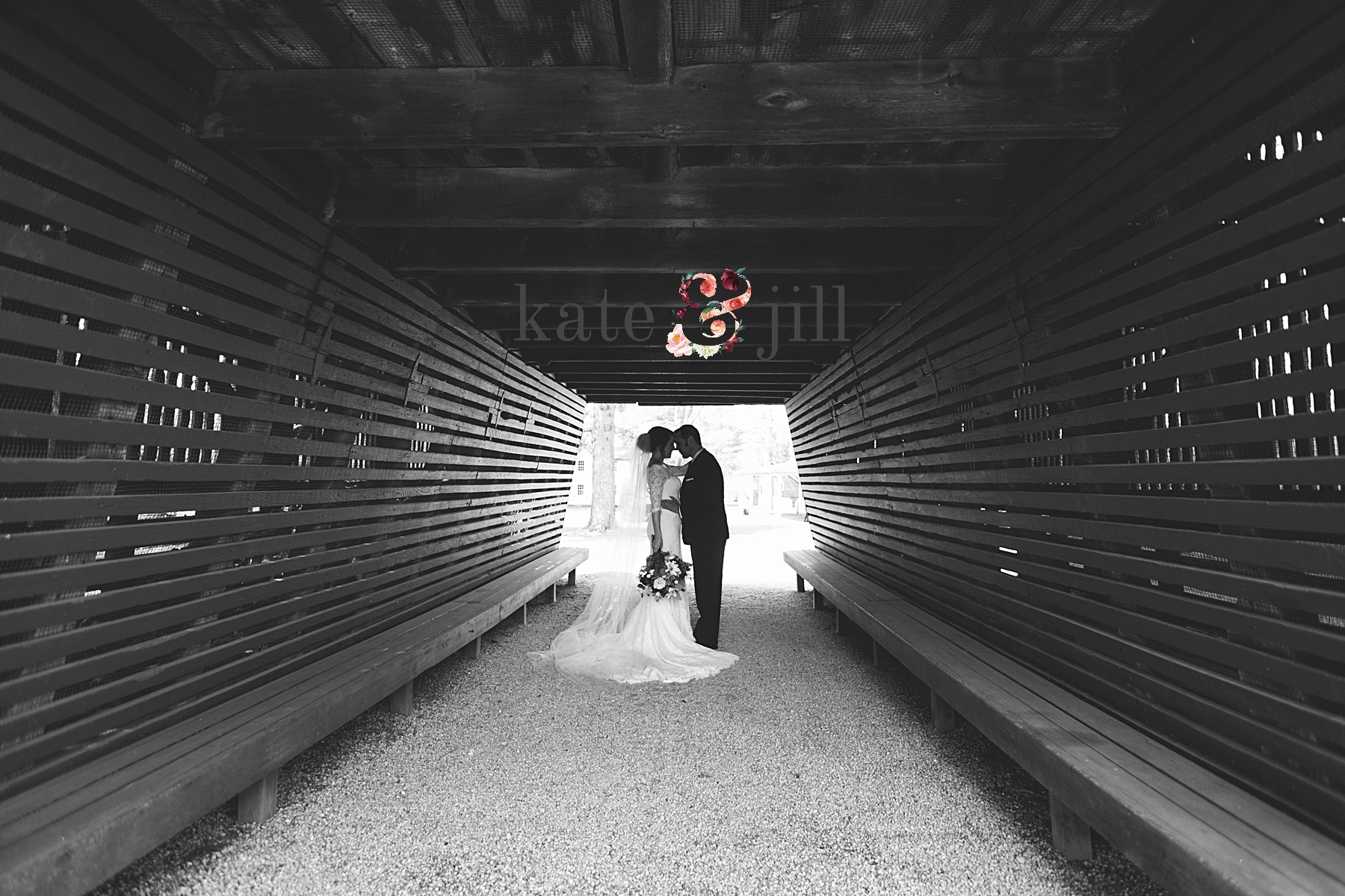 bride and groom kissing under covered bridge
