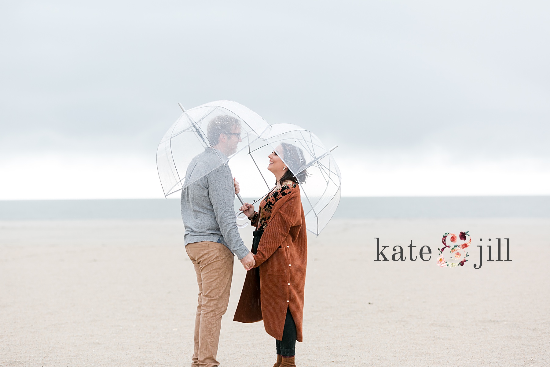 couple holding hands under umbrella rainy engagement session