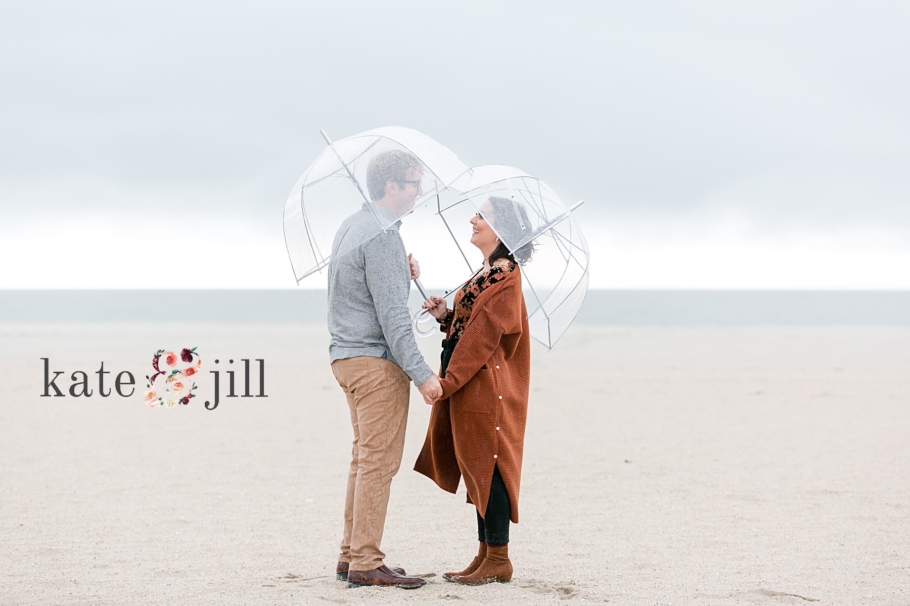 couple holding hands under umbrella rainy engagement session