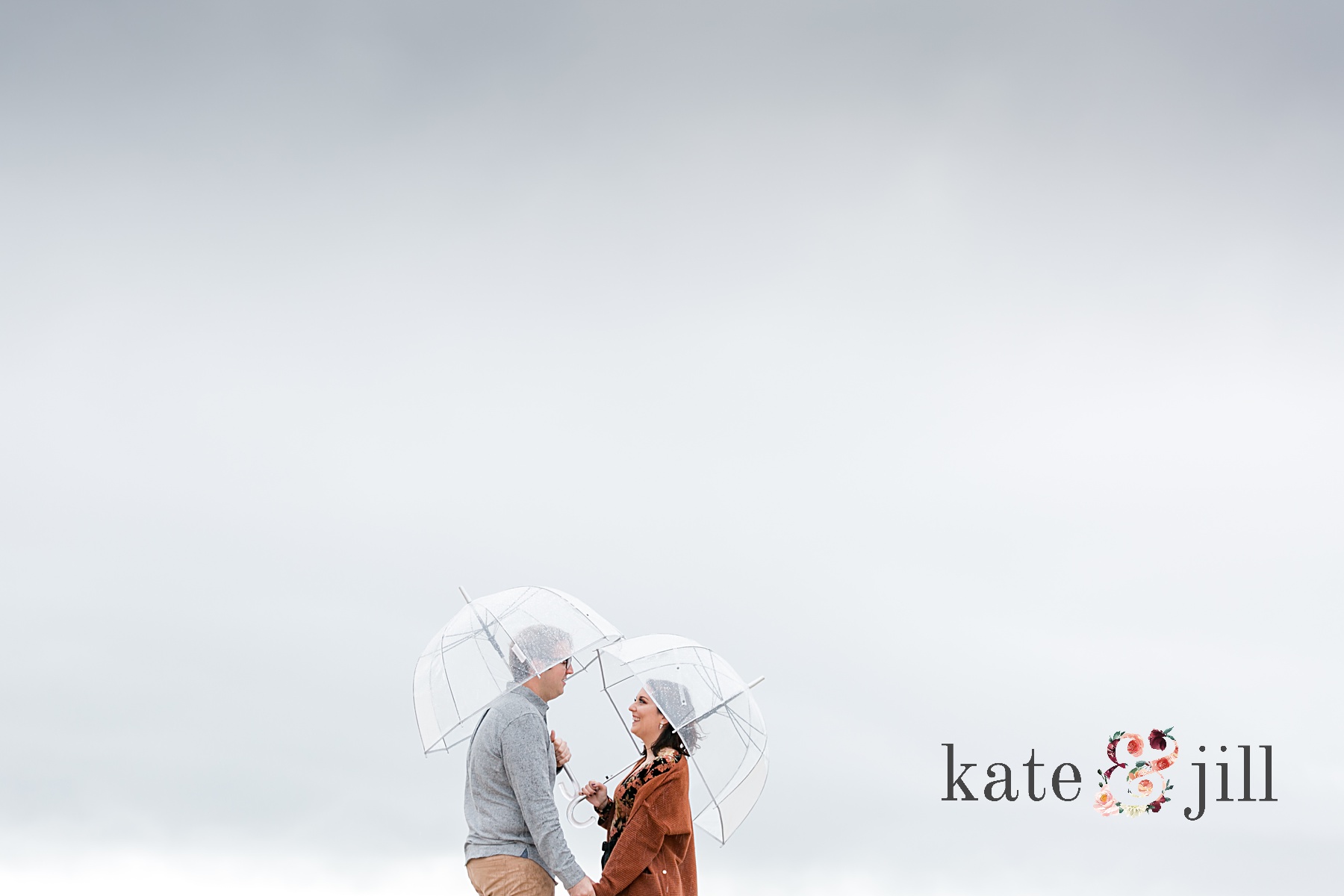couple on beach under umbrella stormy sky rainy