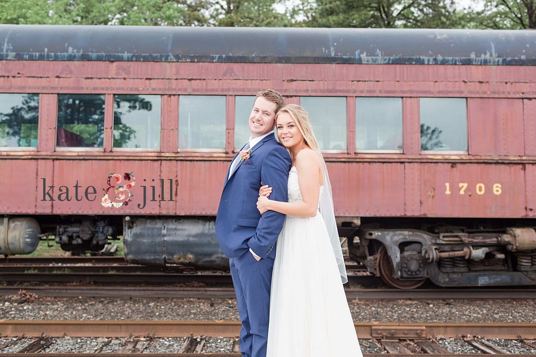 bride and groom in front of train cars at venue