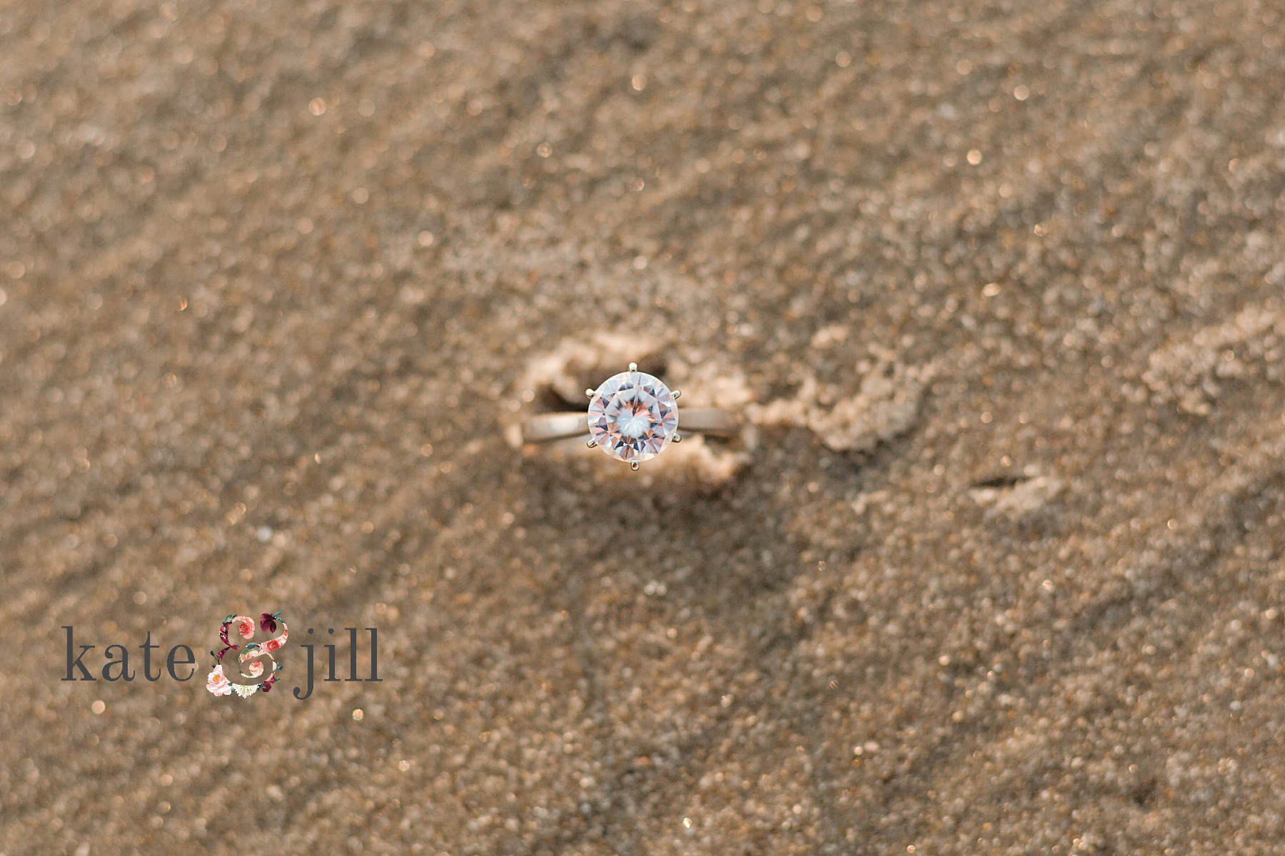 engagement ring in sand on beach